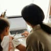 Woman and young girl at a desk in front of a laptop