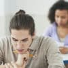 Two students sitting at a desk looking down at their papers while taking a test