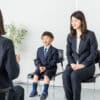 Mother and child dressed up sitting in chairs in front of a woman interviewing them